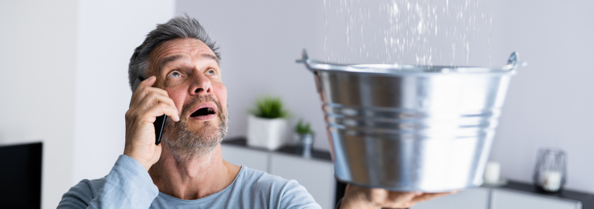 man holding bucket undr leaking pipe