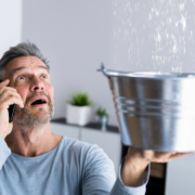 man holding bucket undr leaking pipe
