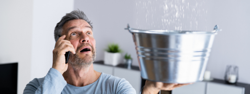 man holding bucket undr leaking pipe