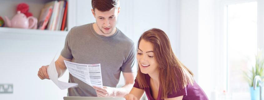 A couple at a laptop happily paying their lower power bills